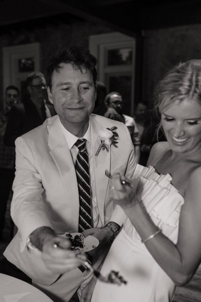 couple laughing and eating cake on their wedding day