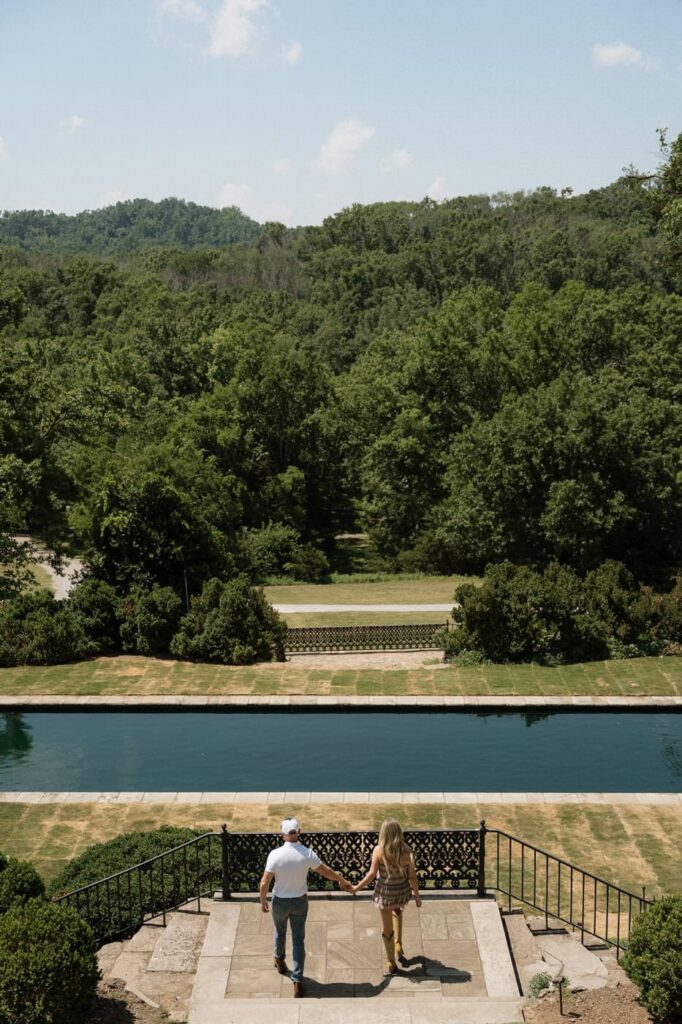 couple holding hands walking towards the reflection pool at cheekwood in nashville