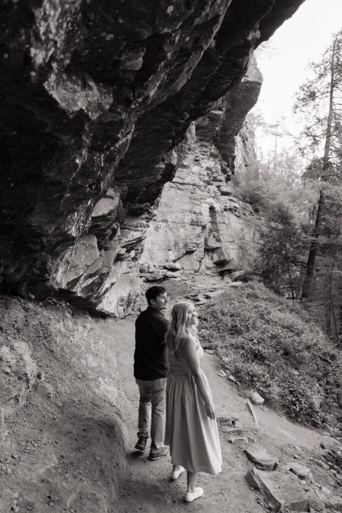 couple looking back at the waterfalls during engagement photos in tennessee