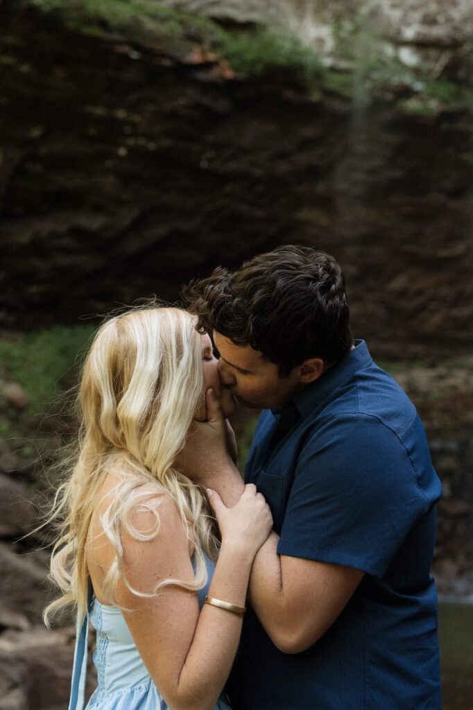 couple kissing at the base of the waterfall during engagement session
