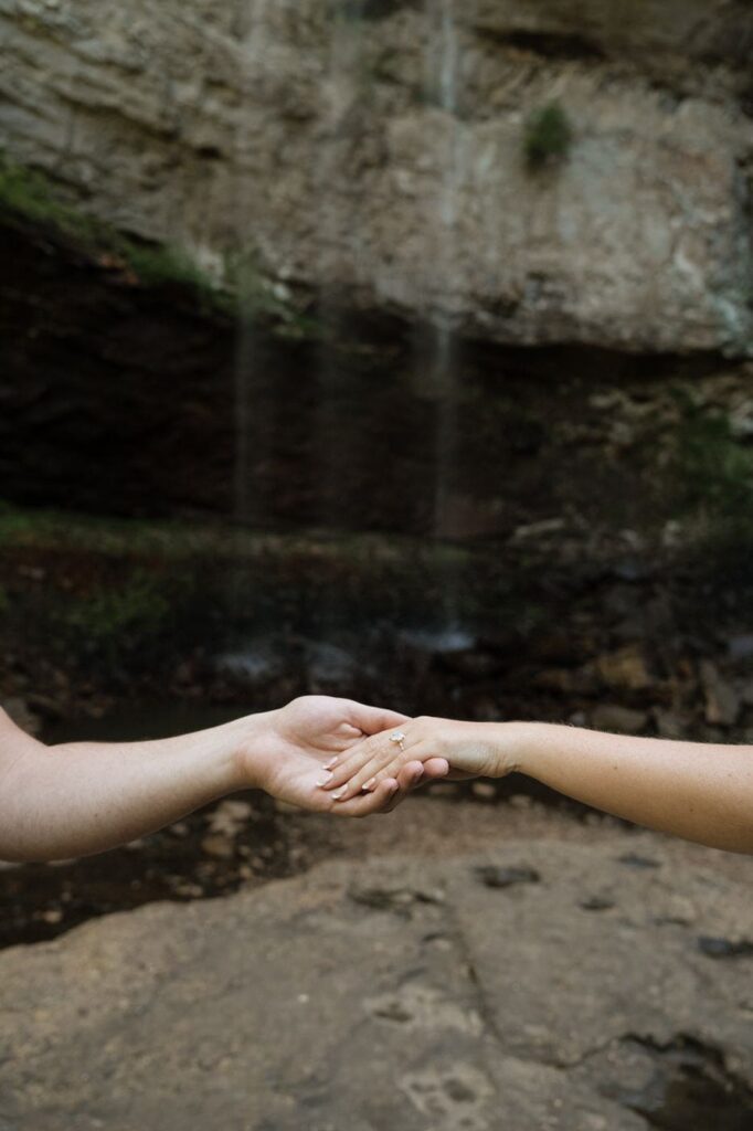 close up of hands with engagement ring at the waterfalls