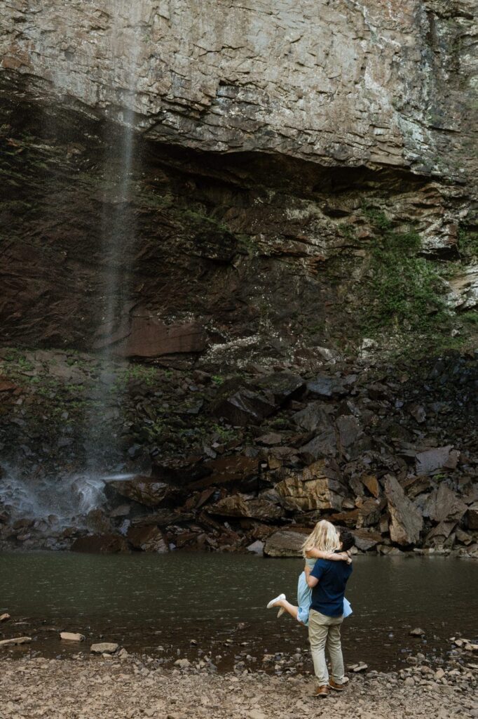 guy picking up his fiance and spinning her at the waterfalls during engagement session
