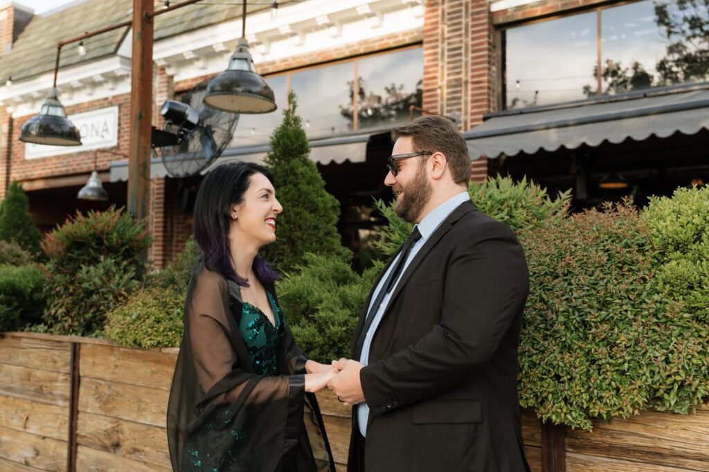 couple holding hands and smiling at each other during engagement photos in nashville