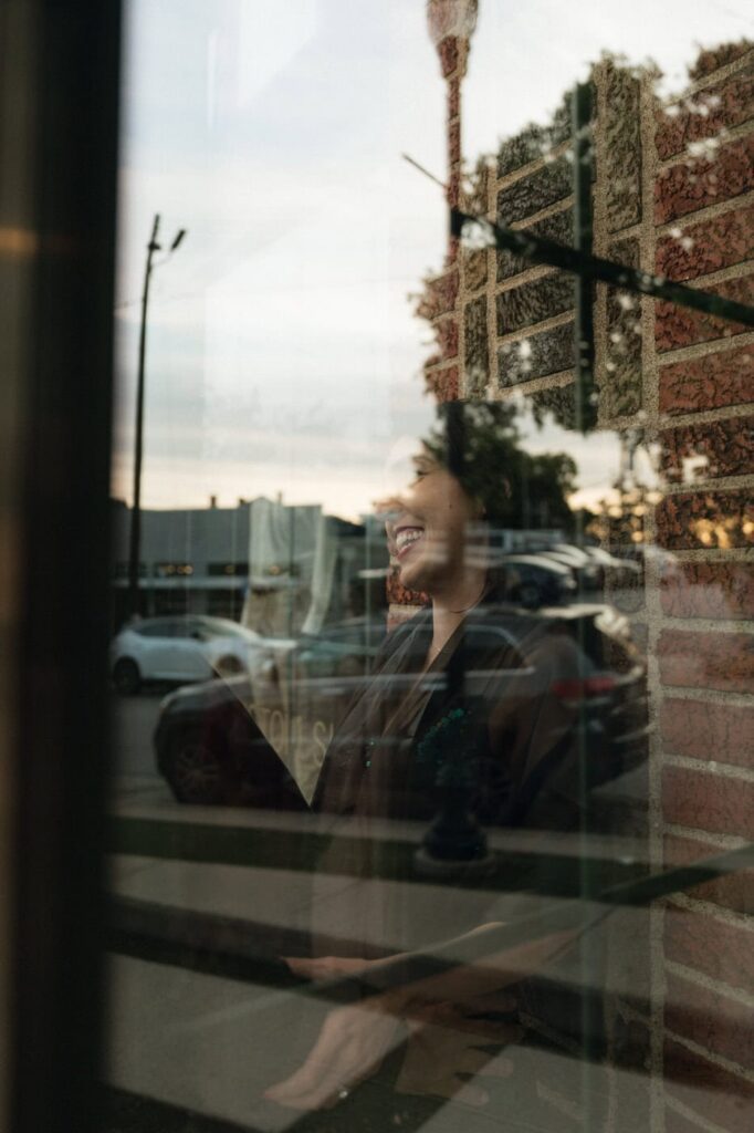 girl smiling through the window reflection