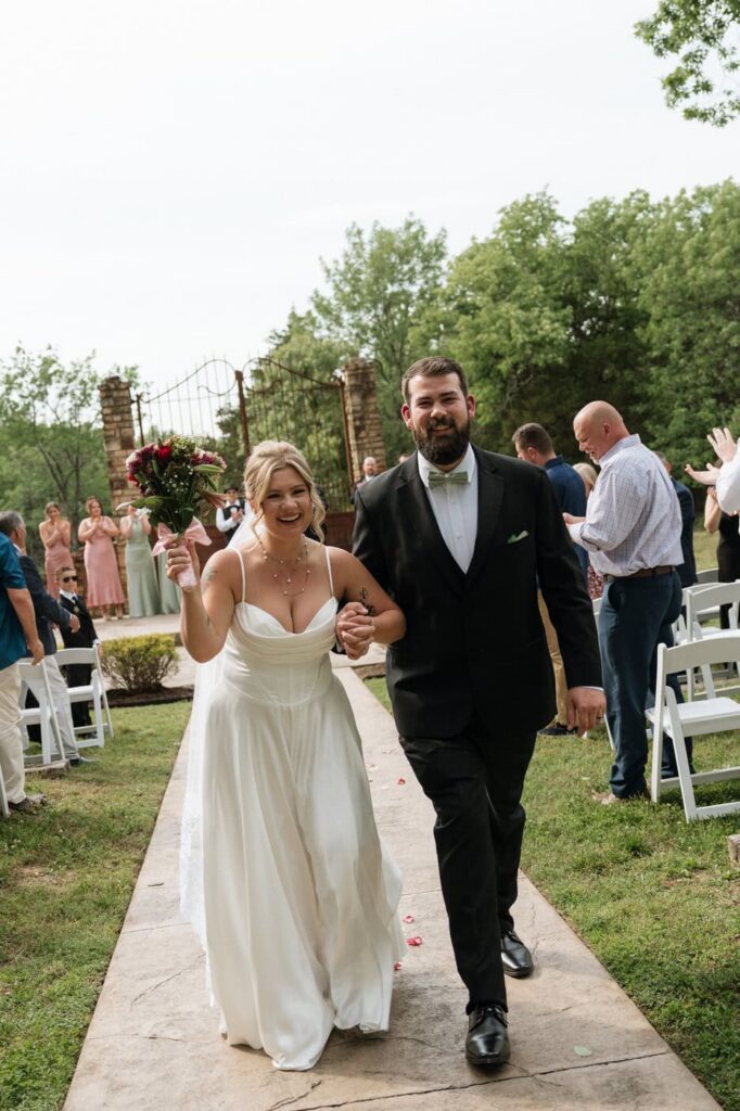 couple laughing and holding hands as they exit the wedding ceremony in nashville