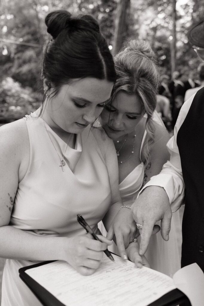 bride and maid of honor signing the marriage license at stone gate farm wedding in nashville