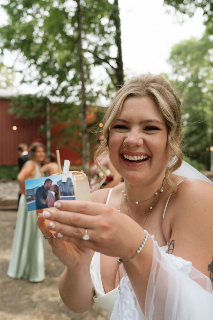 bride smiling and holding up signature cocktail on her wedding day at stone gate farm in nashville
