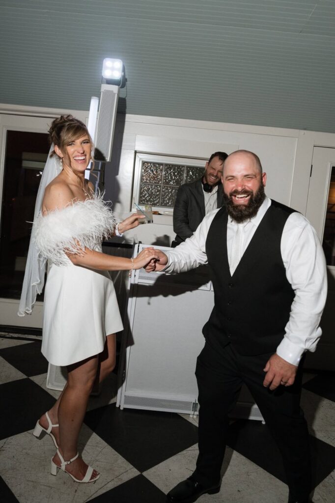 bride and groom laughing with the dj at their wedding reception