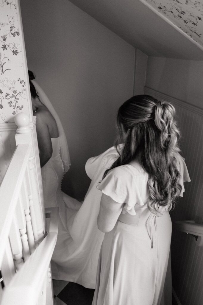 bridesmaid carrying bride's dress down the bridal suite stairs at the estelle in nashville