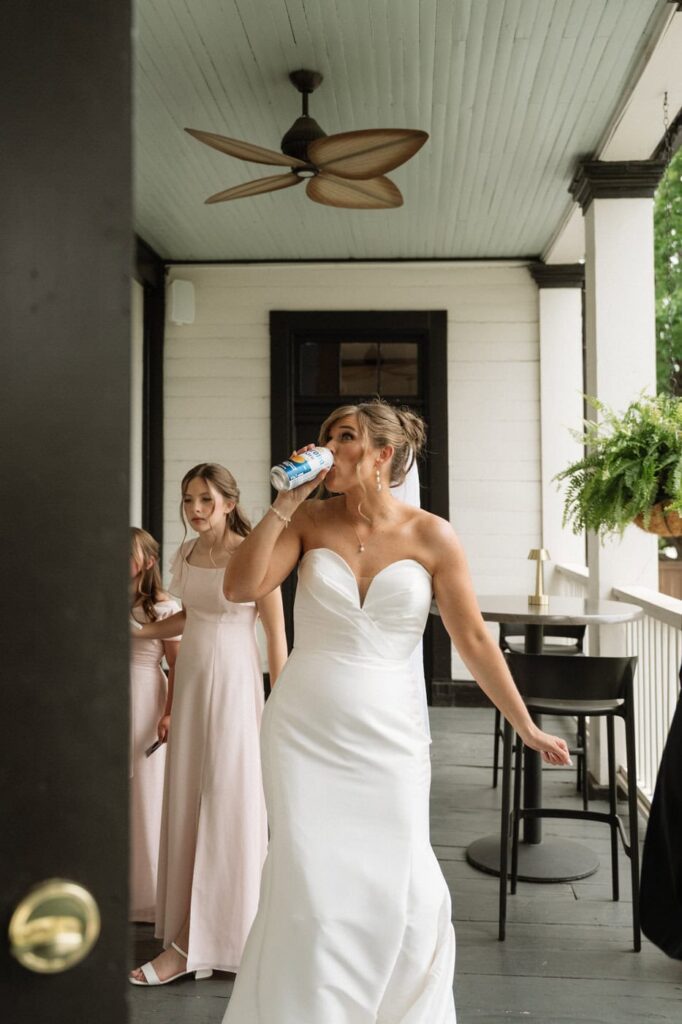 bride drinking a corona on the front porch of wedding venue