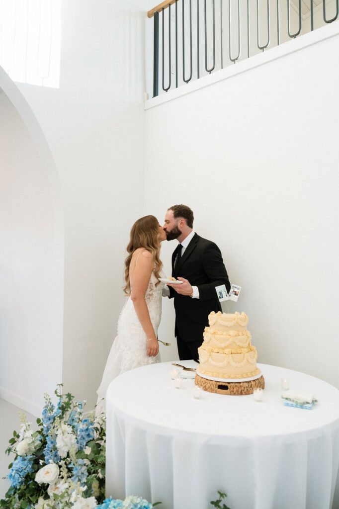 couple kissing after cutting the cake at the monroe on 415th wedding in spring