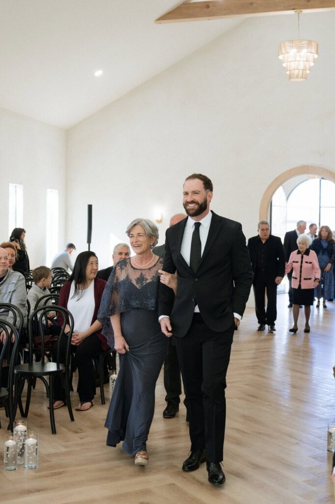 groom and his mother walking down the aisle