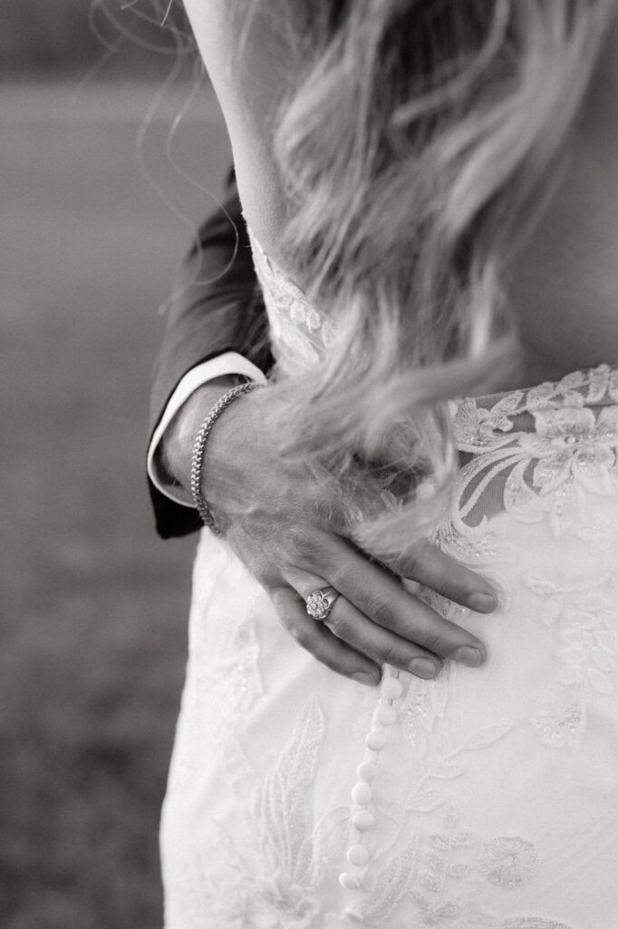 close up of grooms hand holding the bride