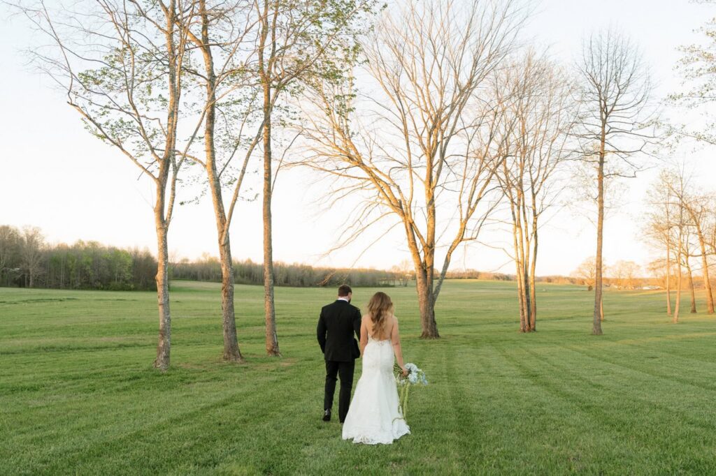 wide shot of couple walking through the fields at sunset at spring nashville wedding