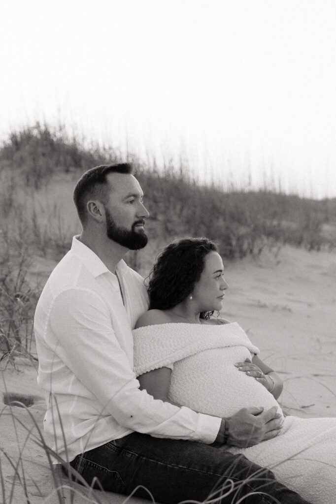 couple looking off into the distance during beach maternity session