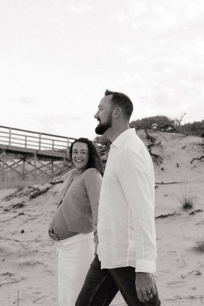 couple holding hands and walking on the beach in virginia