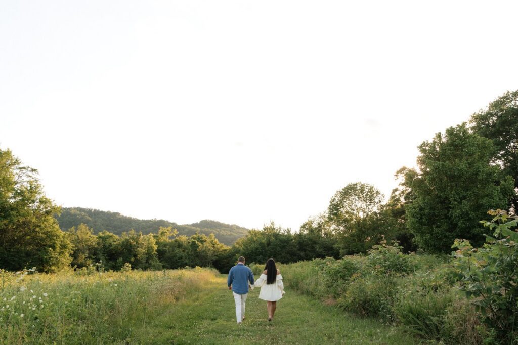 couple holding hands and walking away at golden hour engagement session in nashville