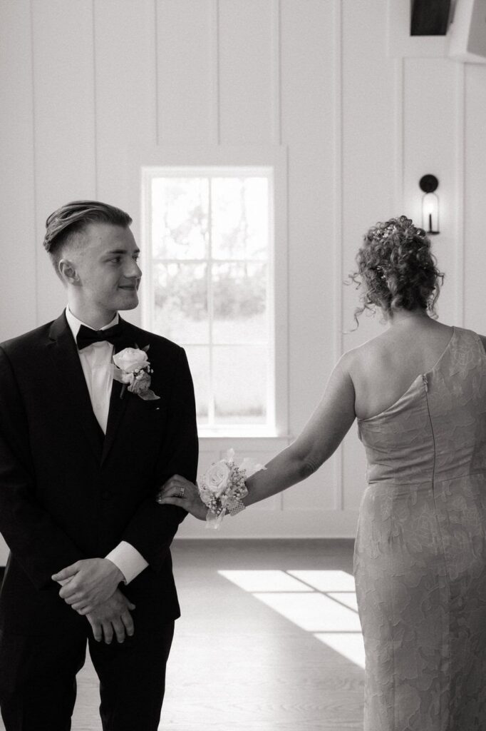 grooms mom touching his arm as she walks down the aisle