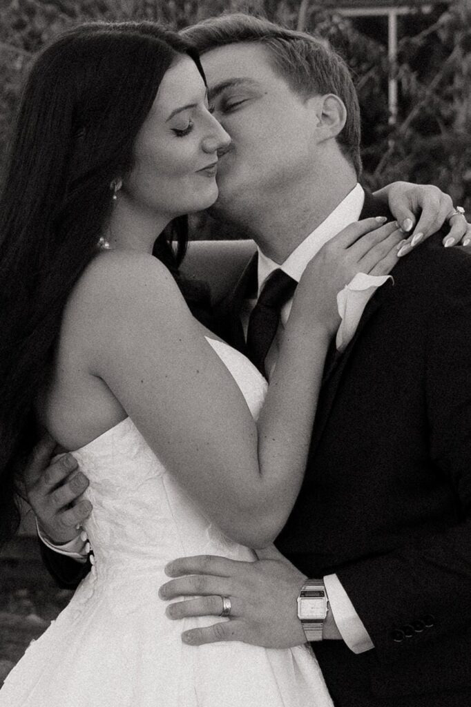 groom kissing bride on the cheek while embracing her at copperline ranch wedding reception