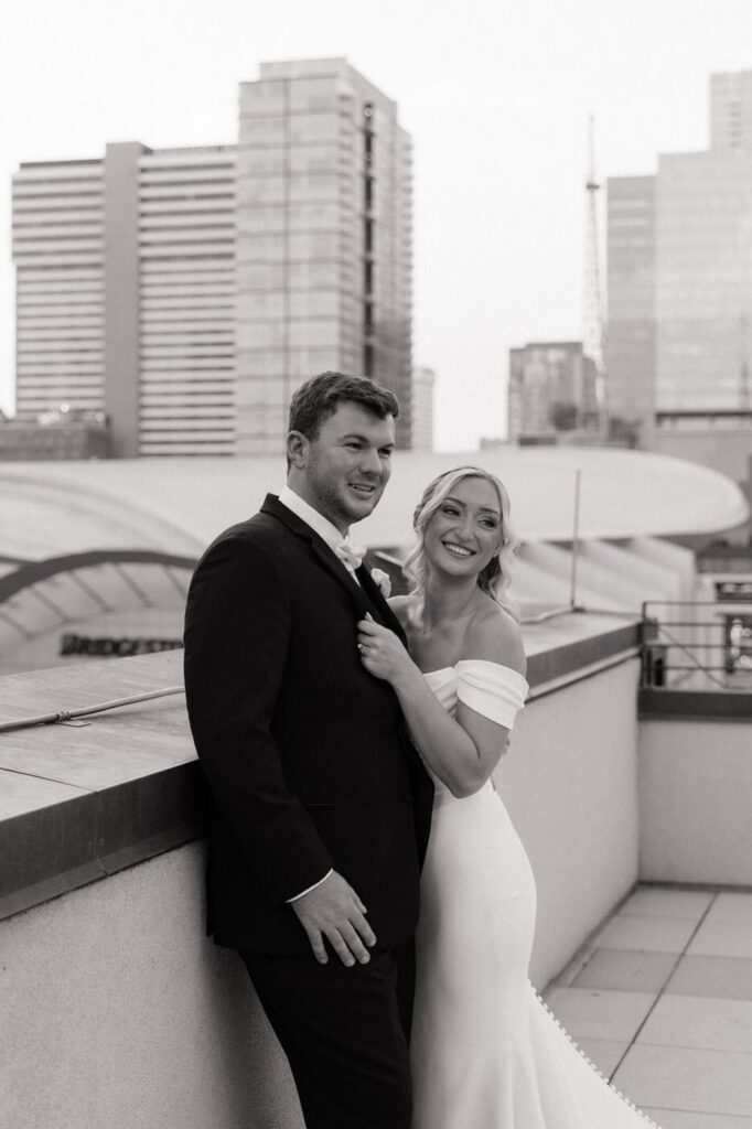 bride and groom smiling at their guests during portraits at the country music hall of fame in nashville